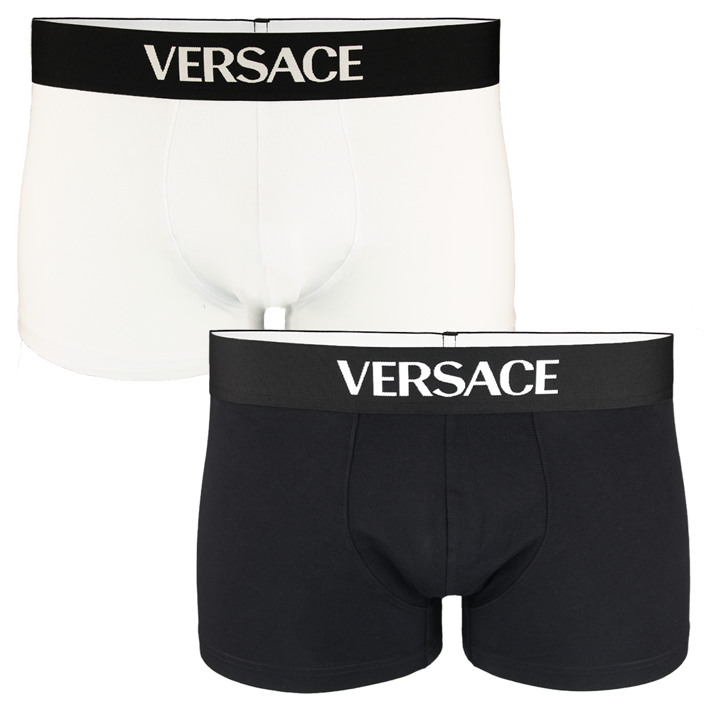 Two pairs of Versace boxer trunks, one black and one white, on a white background.