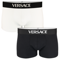 Two pairs of Versace boxer trunks, one black and one white, on a white background.