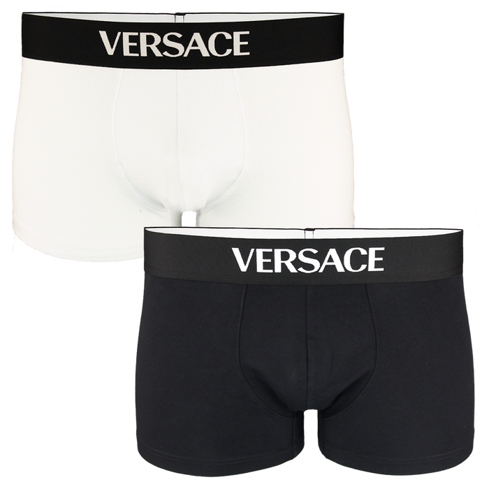 Two pairs of Versace boxer trunks, one black and one white, on a white background.