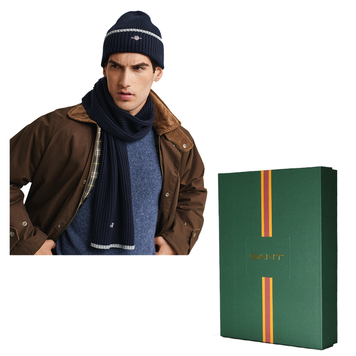 Man wearing a brown jacket, blue scarf, and navy beanie with a GANT branded box on a white background.