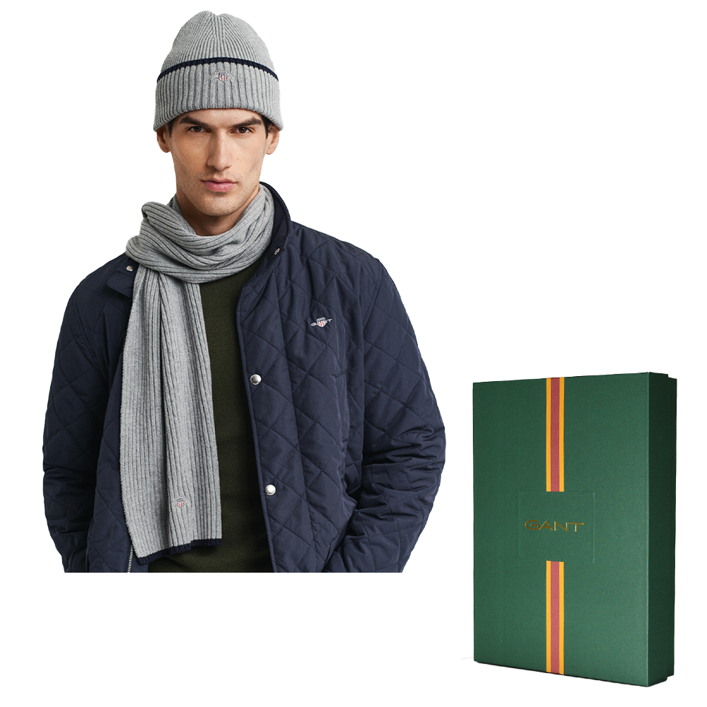 Man wearing a navy quilted jacket, gray knit hat, and scarf with a Gant branded box on a white background.