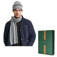 Man wearing a navy quilted jacket, gray knit hat, and scarf with a Gant branded box on a white background.