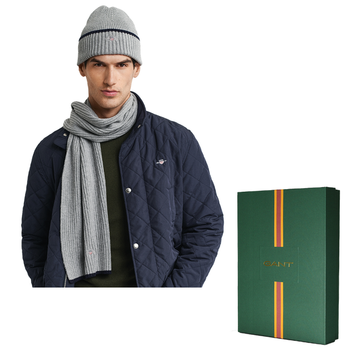 Man wearing a navy quilted jacket, gray knit hat, and scarf with a Gant branded box on a white background.