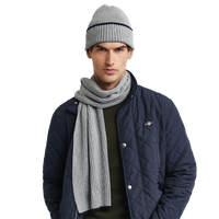 Man wearing a navy quilted jacket, gray beanie, and scarf on a white background