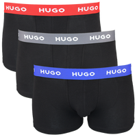 Three black boxer trunks with colorful 'HUGO' brand bands on a white background