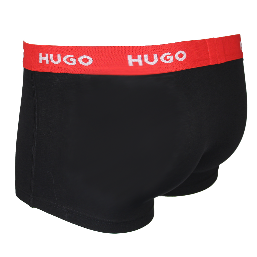 Black boxer trunk with a red waistband featuring 'HUGO' branding on a white background.
