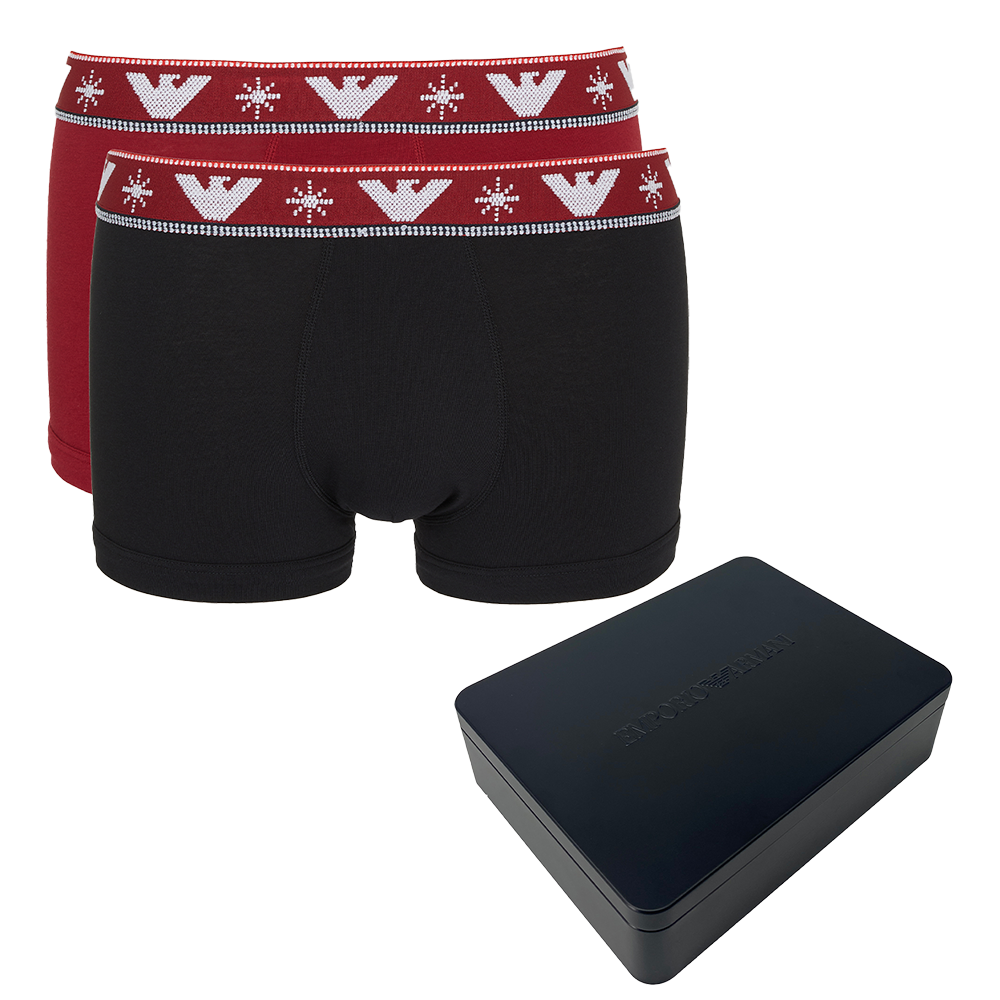 Black boxer trunks with red waistband featuring a logo, next to a black rectangular box on a white background.