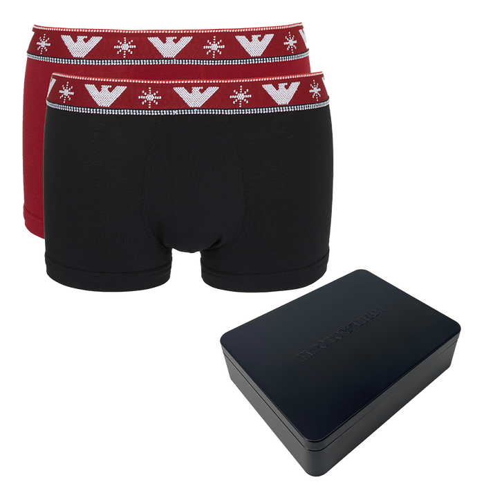 Black boxer trunks with red waistband featuring a logo, next to a black rectangular box on a white background.