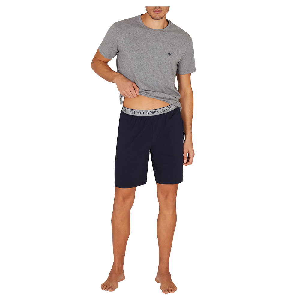 Man wearing a gray t-shirt and navy shorts on a white background