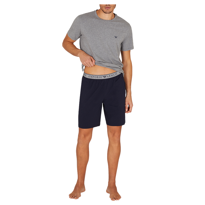 Man wearing a gray t-shirt and navy shorts on a white background
