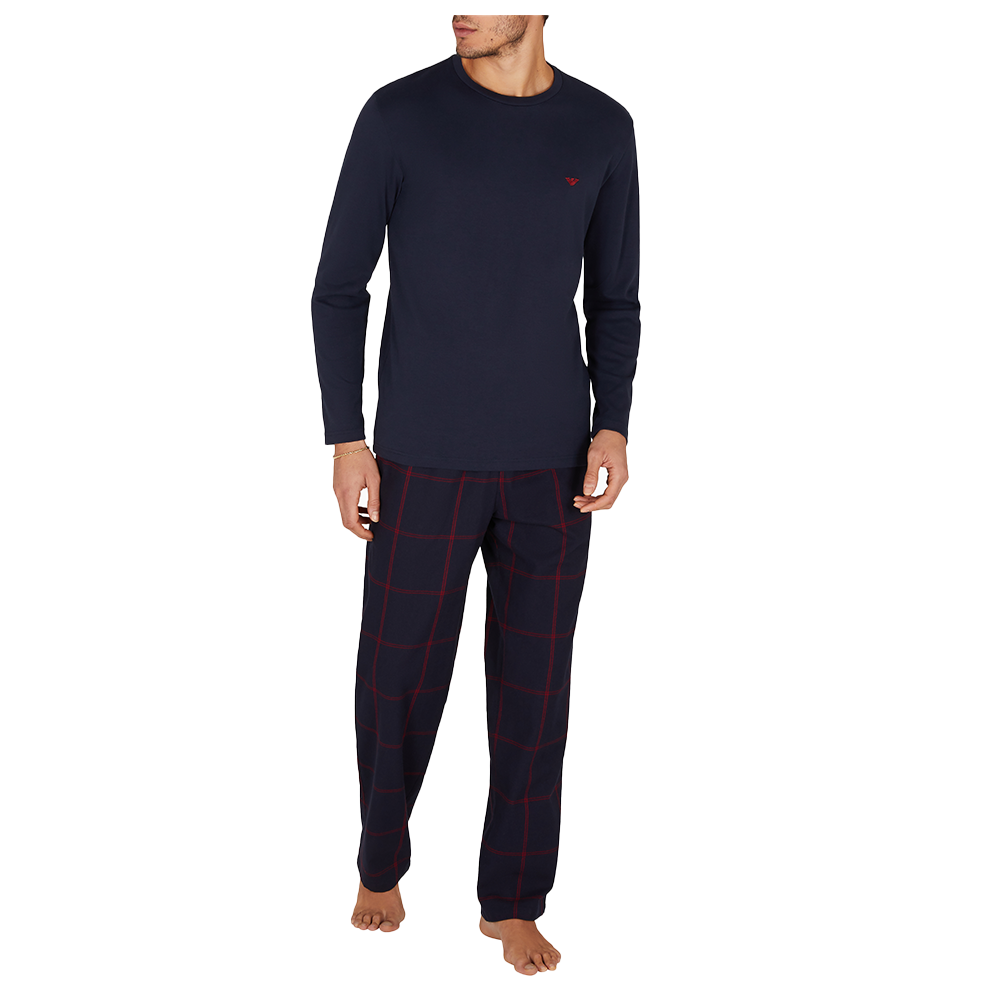 Man wearing navy long-sleeve top and pants with red plaid pattern on a white background