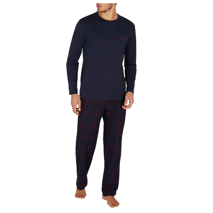 Man wearing navy long-sleeve top and pants with red plaid pattern on a white background