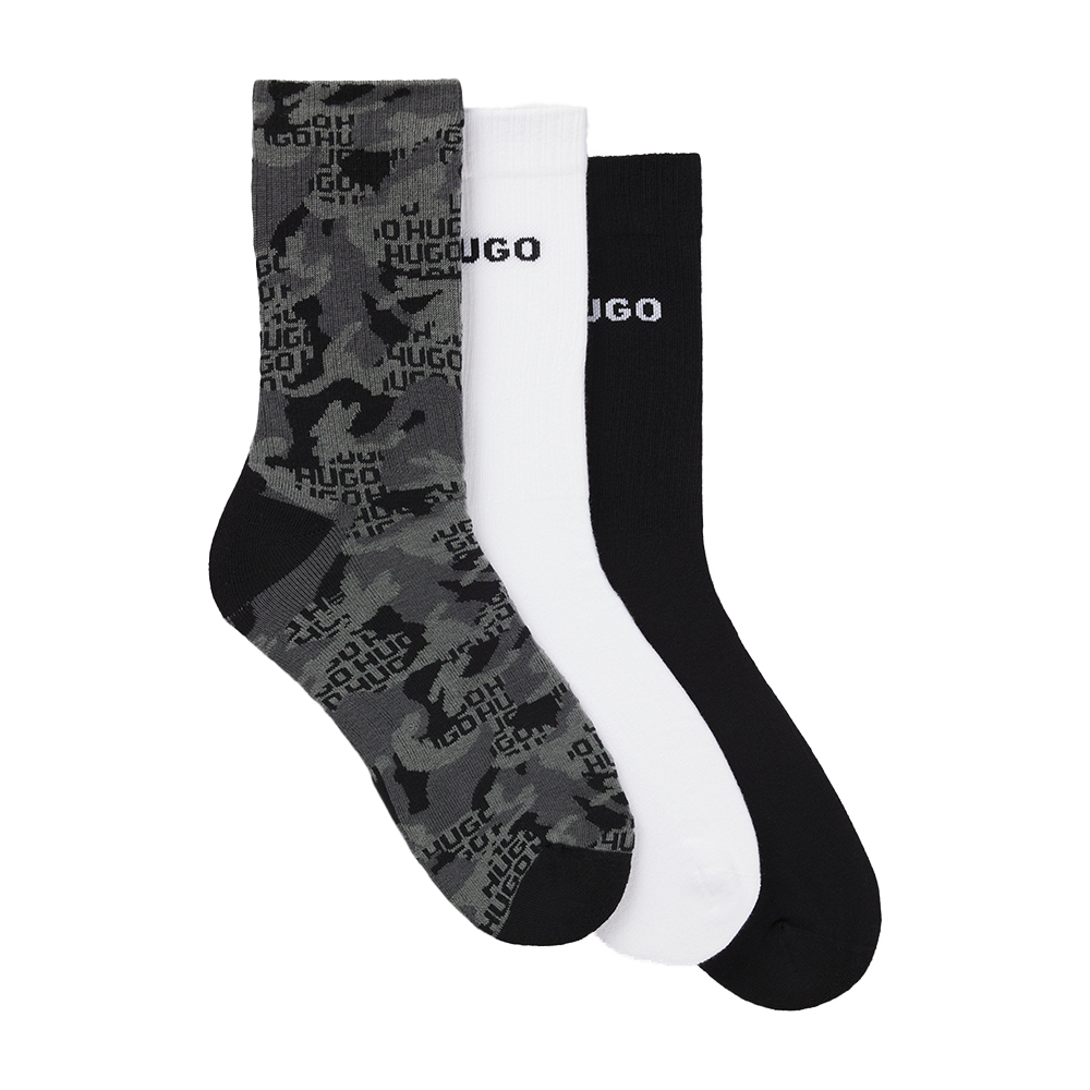 Three pairs of socks in gray camouflage, white, and black with 'HUGO' branding on a white background.