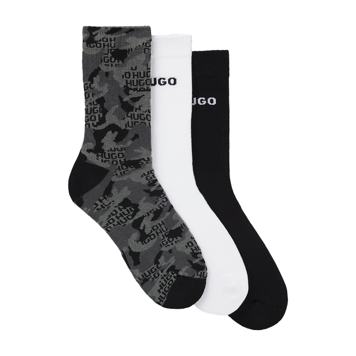 Three pairs of socks in gray camouflage, white, and black with 'HUGO' branding on a white background.