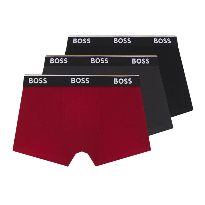 Three pairs of BOSS boxer trunks, black , grey and one red, on a white background.
