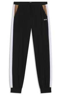Black tracksuit pants with white side stripes on a white background