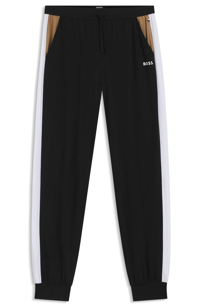Black tracksuit pants with white side stripes on a white background